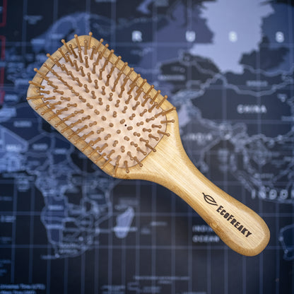 A bamboo hairbrush with a cushioned base background with the word Ecofreaky. It is ecofriendly and stylish.